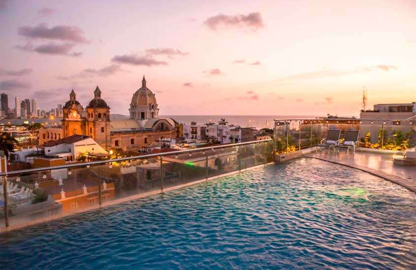 Durante o entardecer, área de lazer de um dos hotéis pasa passar o Réveillon em Cartagena das Índias, com piscina, paisagem da cidade e espreguiçadeiras