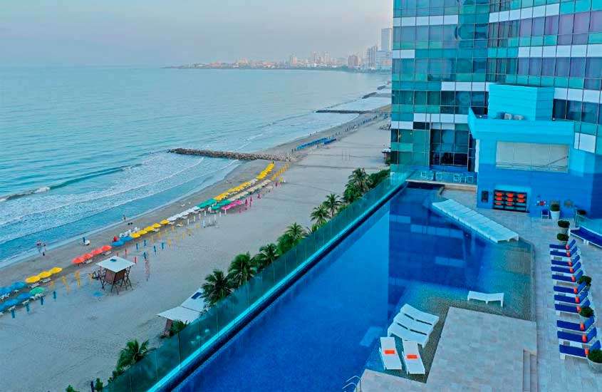 Duratnete o entardecer, área de lazer de um hotel pasa passar o Réveillon em Cartagena das Índias, com piscina, espreguiçadeiras, vista da praia e árvores ao redor