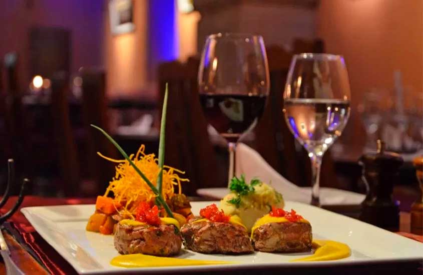 Mesa de jantar do Réveillon em Cusco com taças de vinho e água e prato com carne