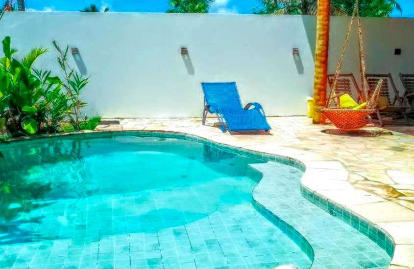 Em um dia ensolarado, área de lazer de um dos hotéis fazenda em Alagoas com piscina, espreguiçadeiras e plantas ao redor