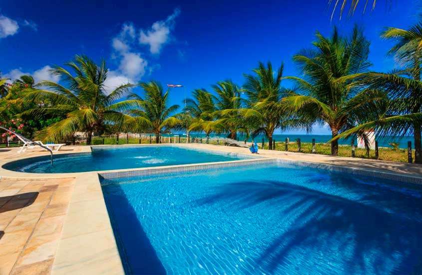 Em um dia de sol, área de lazer de um dos hotéis fazenda em Alagoas com piscinas, árvores ao redor e praia do lado