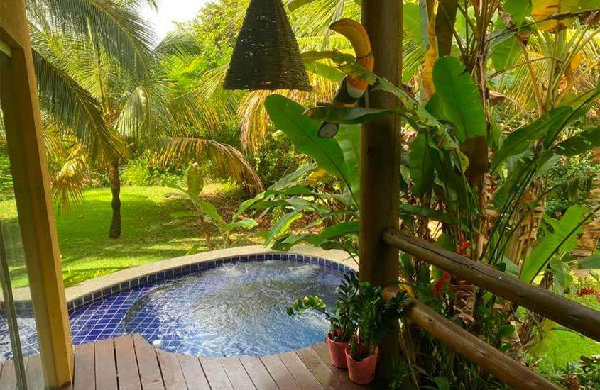 Em um dia de sol, área de lazer de um dos hotéis fazenda em Alagoas com piscina, deck de madeira, árvores e plantas ao redor