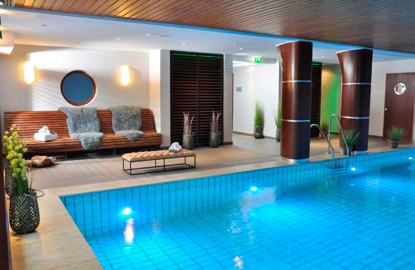 Área de lazer de um hotel em Hamburgo com piscina coberta, sofá, plantas decorativas e banco