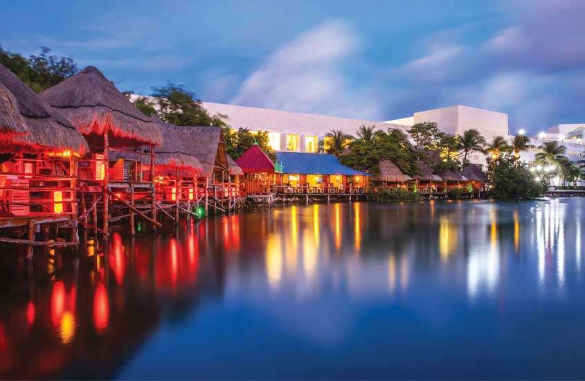 Durante o entardecer, restaurante para passar o Réveillon em Cancún com árvores e mar ao redor