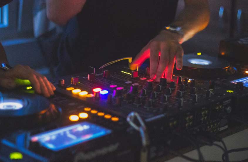 Mesa de DJ com pessoasmexendo e luzes coloridas