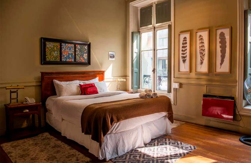 Quarto de hotel para passar o réveillon em santiago com cama de casal, tapetes, quadros decorativos e janelas grandes