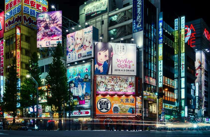 Durante a noite, um dos pontos turísticos préferidos de quem vai viajar para tokyo com prédios iluminados, outdoors, árvores e carros