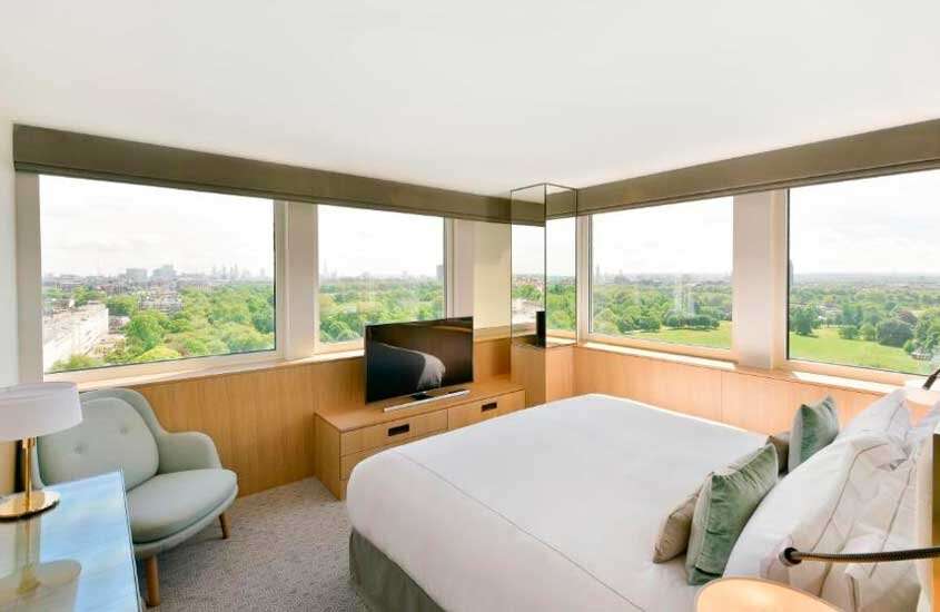 Quarto luxuoso de um dos hotéis em londres para brasileiros, com cama de casal, TV, janelas grandes acortinadas e poltrona