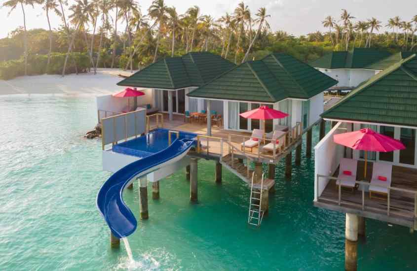 Em um dia de sol, hotel romântico nas Maldivas com toboágua, espreguiçadeiras, guarda-sóis, piscina e escada do lado