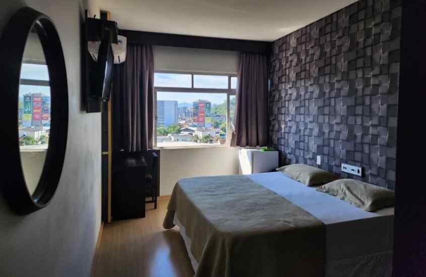 Quarto de um hotel perto da oktoberfest blumenau, com cama de casal, TV, janela com paisagem