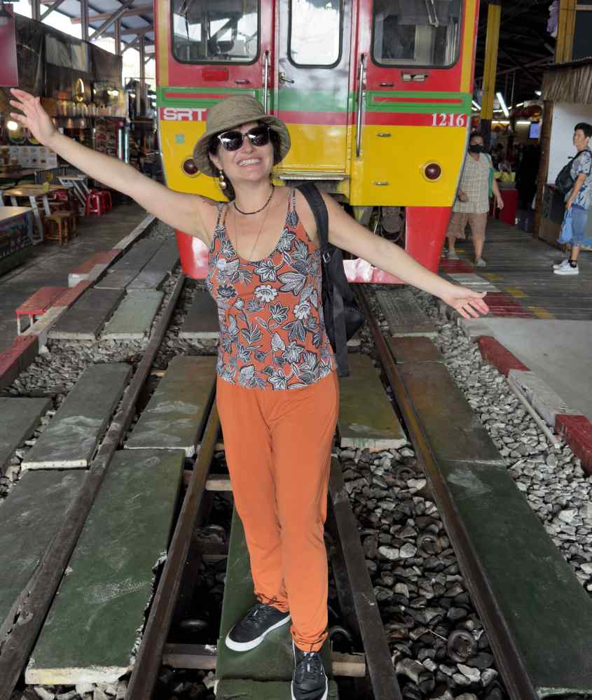 Bárbara Rocha Alcantelado, criadora do blog melhores momentos da vida em Samut Songkran com trem atrás e pessoas ao redor