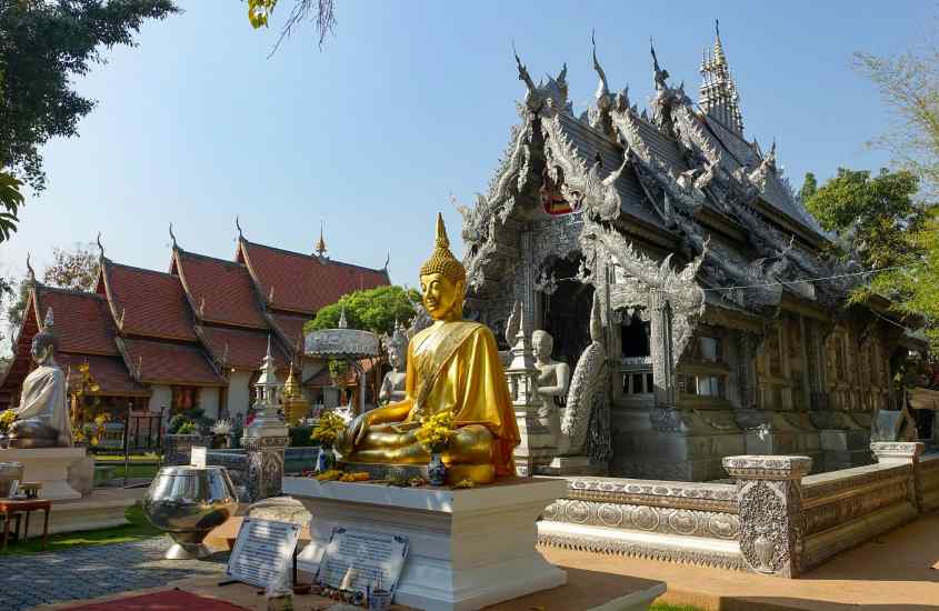 Em um dia de sol, Wat Phrathat Doi Suthep com estátua de ouro, árvores e pessoas ao redor
