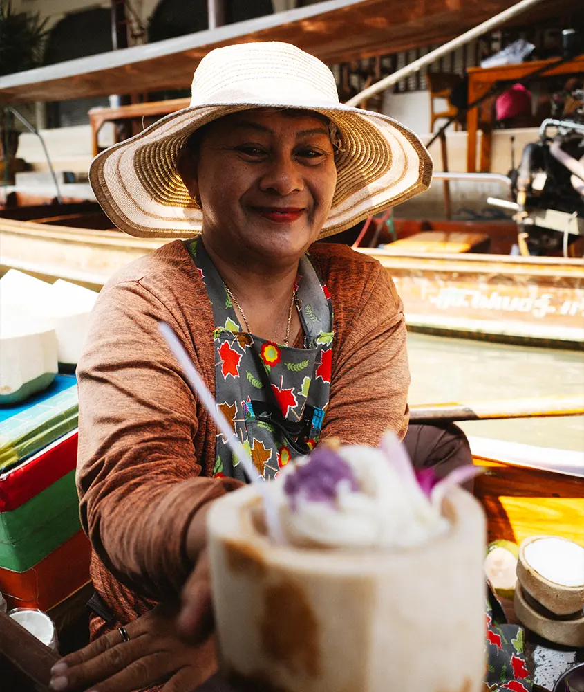 Em um dia de sol, tailandesa em barco com mercado atrás