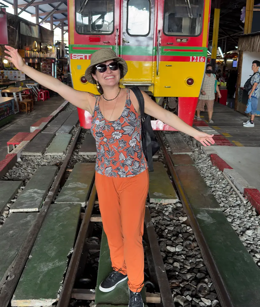 Bárbara Rocha Alcantelado, criadora do blog melhores momentos da vida em Samut Songkran com trem atrás e pessoas ao redor