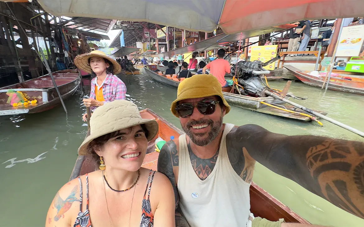 Em um dia de sol, Bárbara Rocha Alcantelado e Vagner Alcantelado em um barco em mercado flutuante da Tailândia