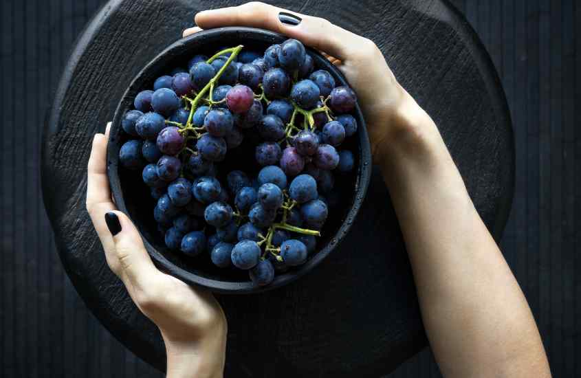 Mulher segurando vasilha de uvas