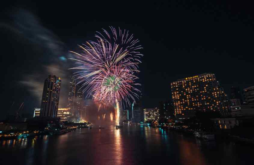 Durante a noite, queima de fogos do Réveillon na Tailândia em Bangkok com prédios iluminados ao redor