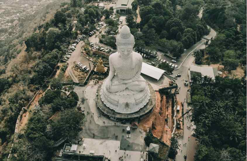 Em um dia de sol, templo em Phuket com pessoas e árvores ao redor, uma das cidades para comemorar o Réveillon na Tailândia