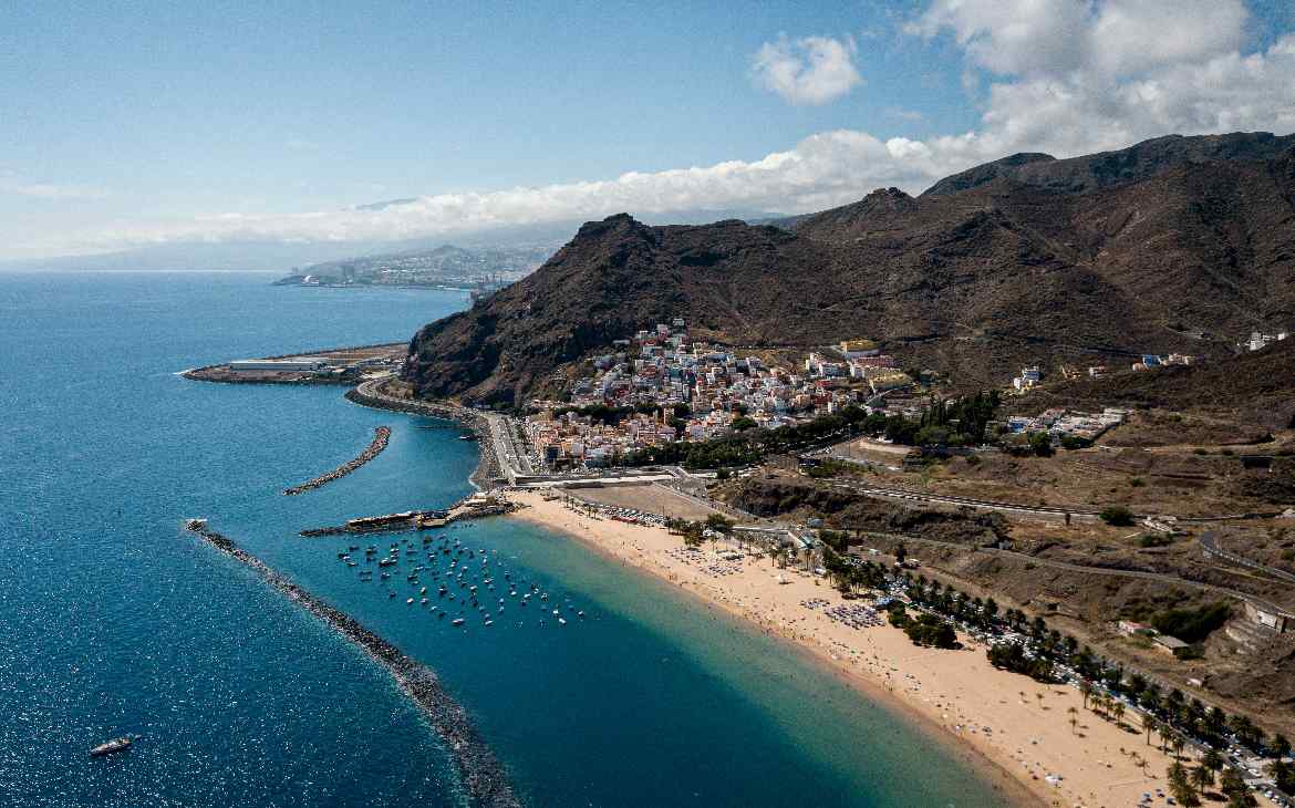 Em um dia ensolarado, visão aérea de San andres com montanhas de um lado e praia do outro