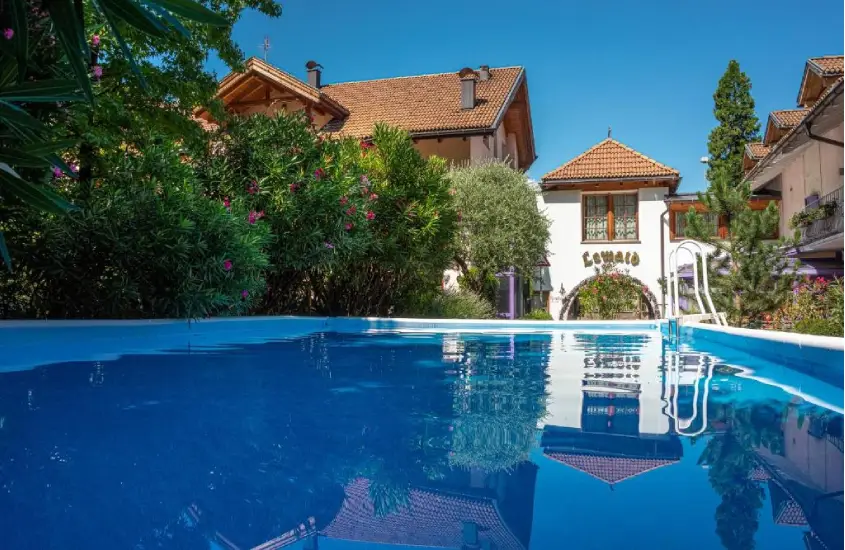 Piscina externa com água azul e vista para montanhas em um dia ensolarado em Bolzano