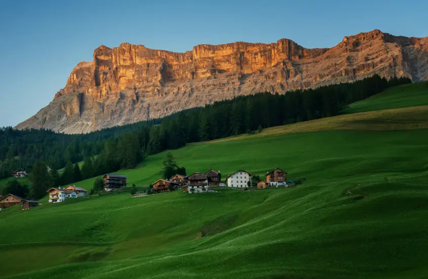 Paisagem de Alta Badia, um destino perfeito para atividades ao ar livre nas Dolomitas, com vilas charmosas e montanhas ao fundo