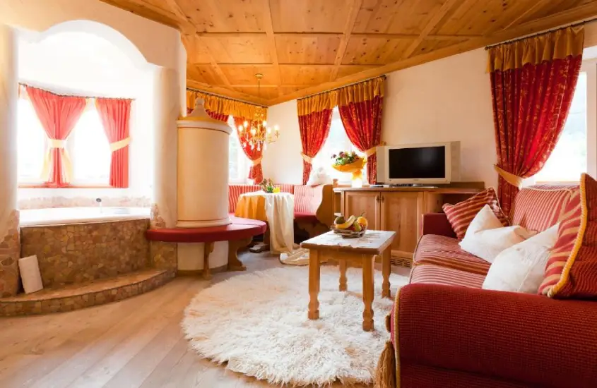 Sala de estar acolhedora com decoração alpina, incluindo sofá, TV e lareira, em San Martino di Castrozza.