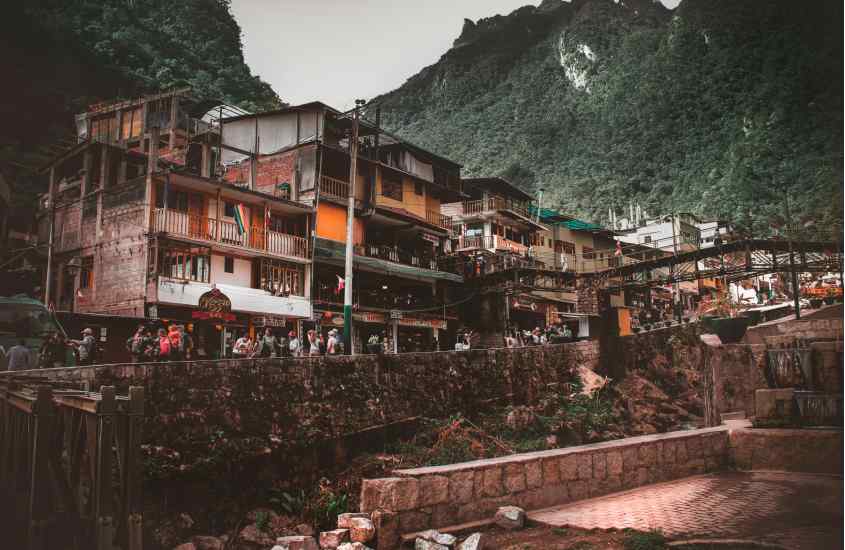 Durante um dia nublado, paisagem de Águas Calientes, um cidade próxima a machu picchu com casas, árvores e montanhas ao redor