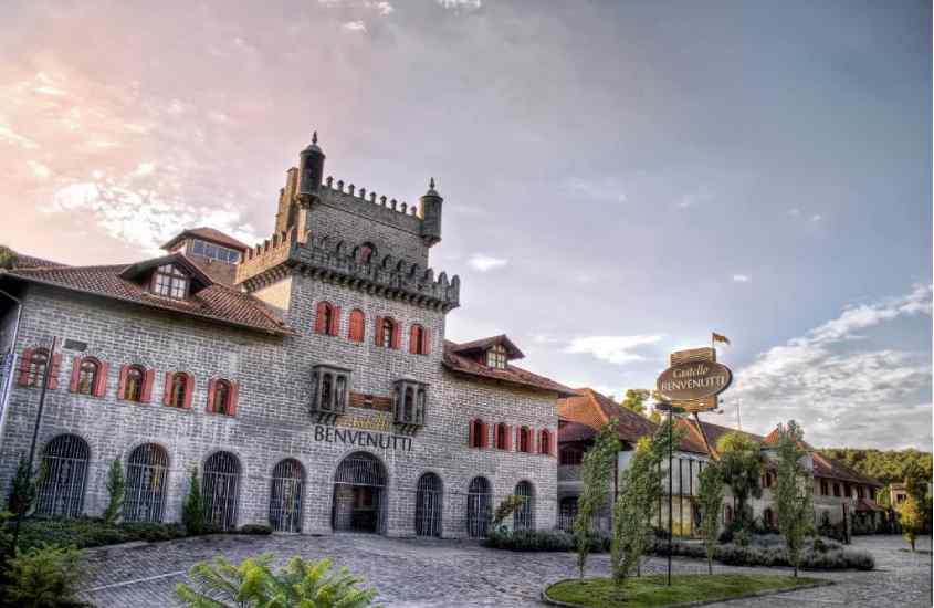 Durante o entardecer, fachada de uma pousada com árvores ao redor e fachada de pedra