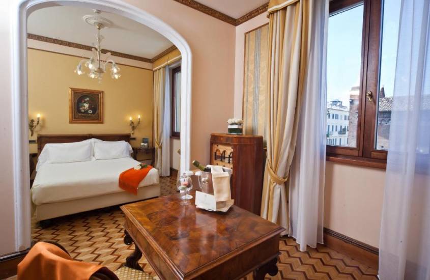 Hotel de um dos lugares para lua de mel internacional com mesa, cadeiras, cama de casakm balde de champagne e janelas grandes acortinadas