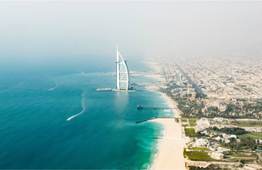 Em um dia de sol, paisagem de dubai, um dos melhores lugares para lua de mel internacional com cidade de um lado e praia do outro