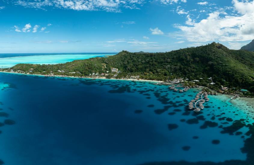 Em um dia de sol, paisagem de Bora Bora, um dos lugares para passar a lua de mel com montanhas do lado e praia na frente