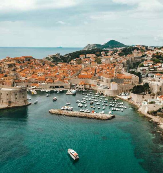 Em um dia nublado, vista aérea de Dubrovnik com praia, barcos, casas e árvores ao redor