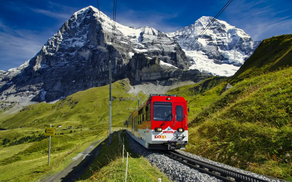 Durante o dia, trem nos Alpes Suíços com montanhas ao fundo