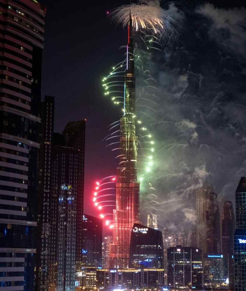 Durante a noite, queima de fogos do Réveillon em Dubai no Burj Khalifacom prédios iluminados ao redor