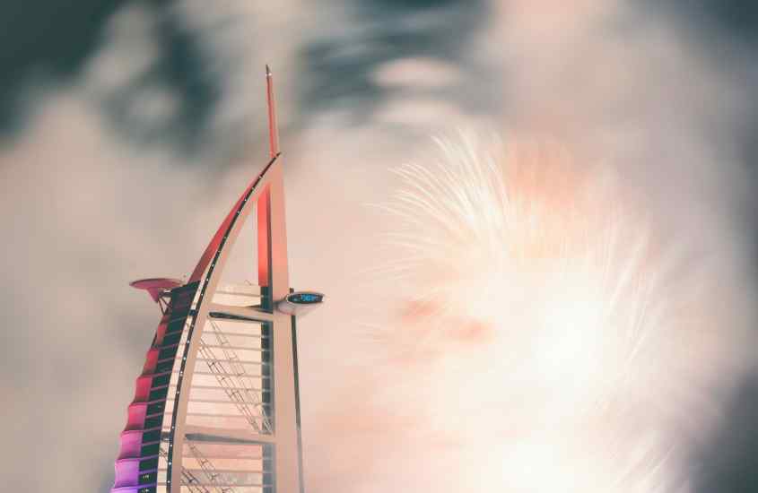 Durante a noite, queima de fogos do Réveillon em Dubai com Burj Al Arab do lado