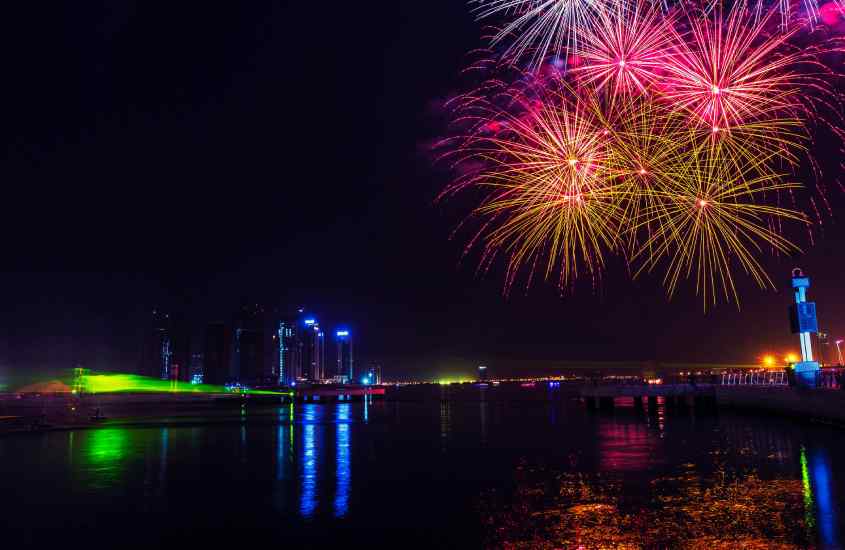 Durante a noite, queima de fogos durante o Réveillon em Dubai com cidade iluminada no fundo