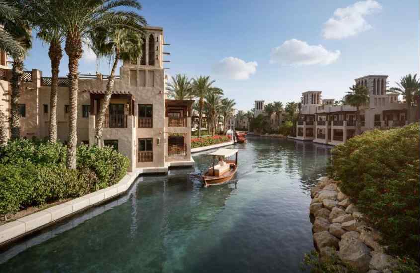 Em um dia de sol, lago de um hotel onde passar reveillon em Dubai com árvores e construções ao redor