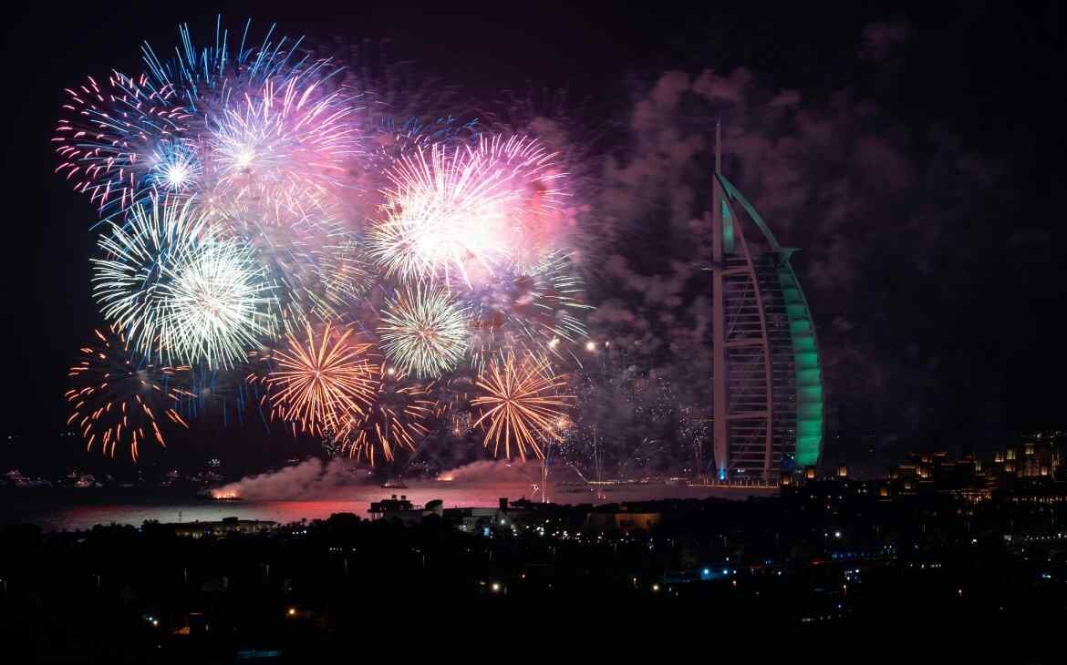 Durante a noite, queima de fogoso durante o Réveillon em Dubai com cidade iluminada ao redor