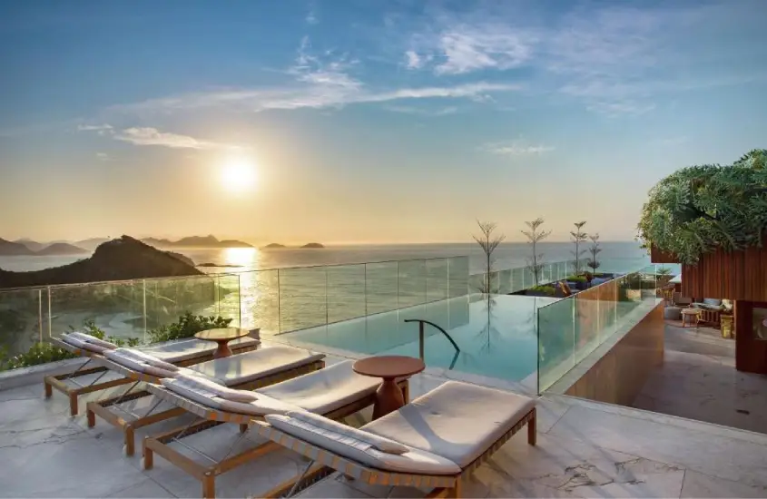 Piscina infinita no Hilton Copacabana com espreguiçadeiras e vista para o mar ao entardecer