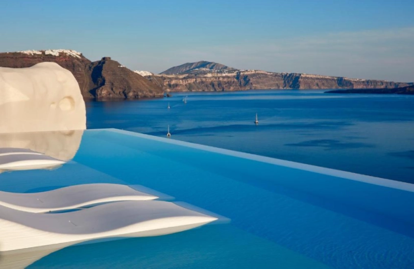 Piscina infinita com vista para o mar e formações rochosas em Santorini, Grécia