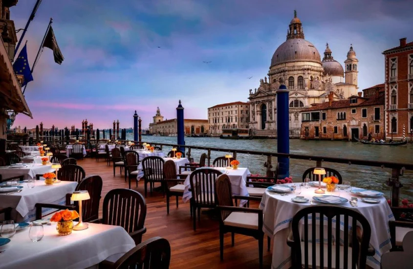 Restaurante ao ar livre à beira do canal com vista para a Basílica de Santa Maria della Salute em Veneza, Itália