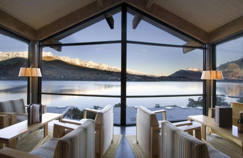 Sala de estar com janelas panorâmicas e vista para o lago Wakatipu e as montanhas Remarkables em Queenstown, Nova Zelândia