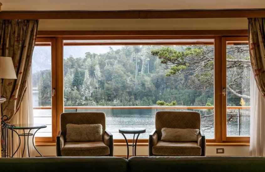 Sala de estar com janelas amplas e vista para o lago e floresta no Llao Llao Resort, Golf-Spa, Bariloche, Argentina