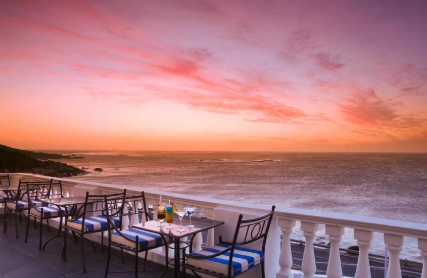 Terraço com mesas e cadeiras com vista para o mar e o pôr do sol em Cape Town, África do Sul