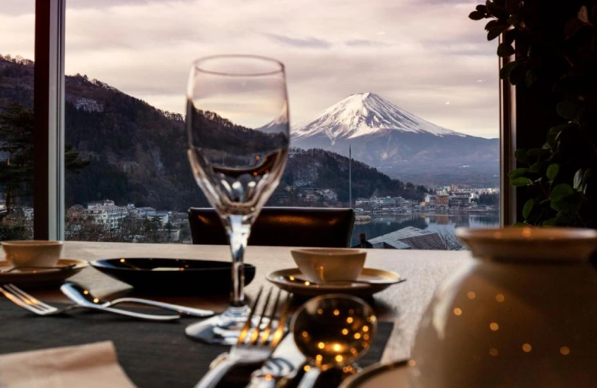 Mesa de jantar elegante com taças de vinho e vista direta para o Monte Fuji coberto de neve em um dos hotéis com as melhores vistas do mundo