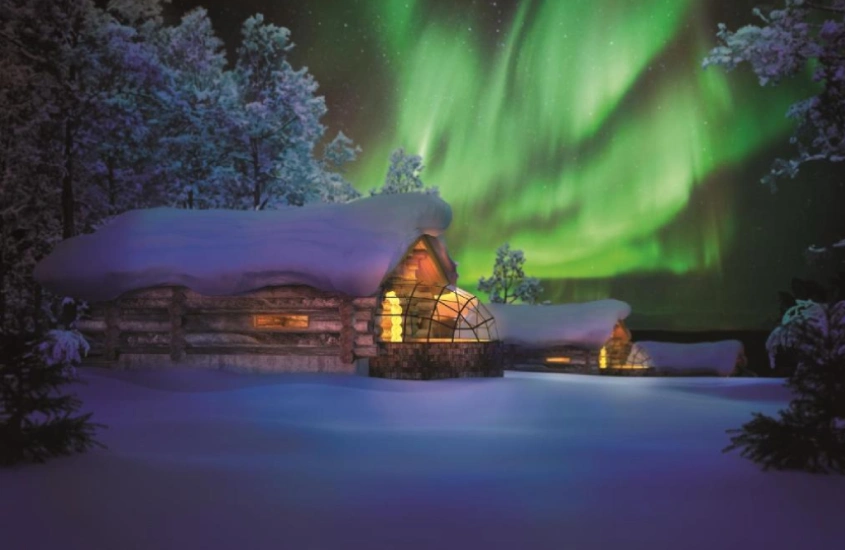 Cabana de vidro coberta de neve com a aurora boreal ao fundo na Lapônia, Finlândia