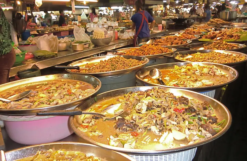 Uma ampla variedade de pratos tailandeses preparados e prontos para serem servidos em uma barraca de comida no Thanin Market