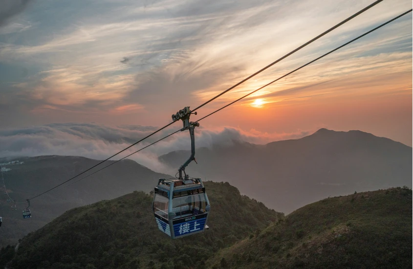 Teleférico cruzando montanhas ao pôr do sol em Hong Kong