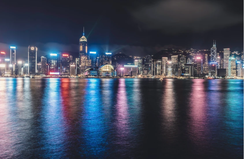 Skyline de Hong Kong iluminado à noite, refletido no mar