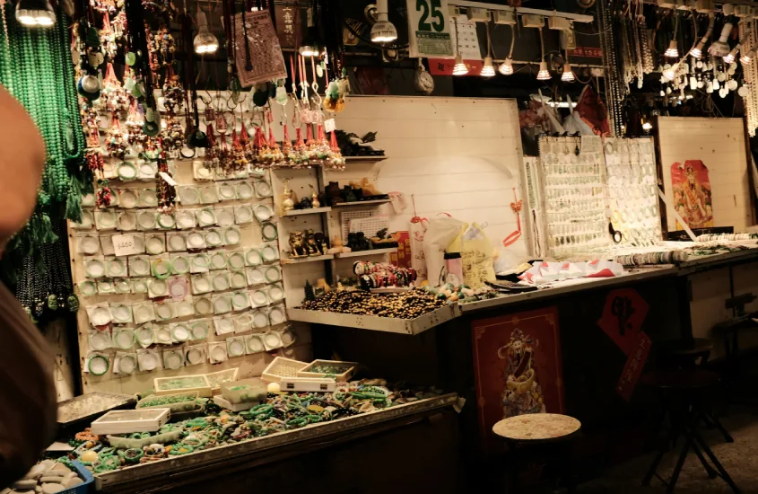 Banca de souvenirs em um mercado noturno de Hong Kong, com jade e outras peças expostas